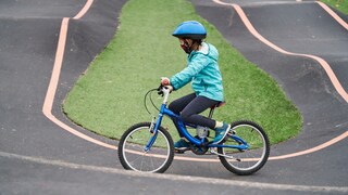 Ein Kind fährt mit einem Fahrrad auf dem Pumptrack