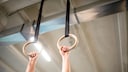 Ring Muscle-ups: Ein Mann fässt zwei Trainingsringe an