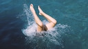 Eine Frau macht einen Kopfsprung in einen See