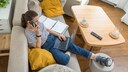Frau telefoniert mit geschientem Bein auf dem Sofa