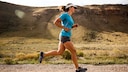 Eine Frau in Sportkleidung joggt durch eine trockene Landschaft