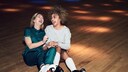 Zwei junge Frauen mit Rollschuhen sitzen lachend auf dem Boden