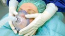 Lachgas Depressionen: Einer Patientin wird eine Atemmaske zur Inhalation im OP-Saal auf das Gesicht gehalten