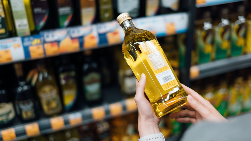 Frau im Supermarkt hält sieht sich die Rückseite einer Flasche Öl an