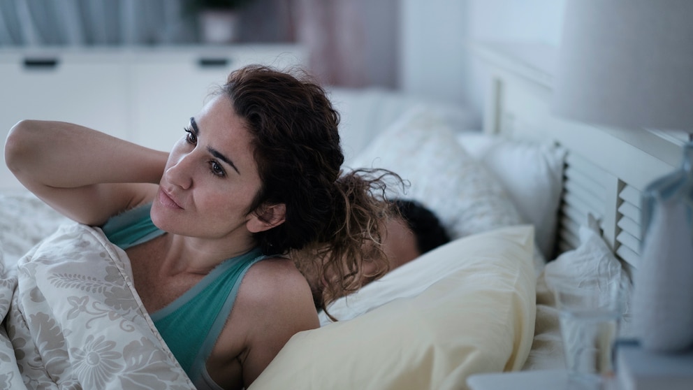 Frau wach neben ihrem Partner im Bett