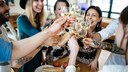 Junge Leute sto&szlig;en mit Wei&szlig;wein an