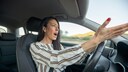 Frau gestikuliert wütend am Autosteuer