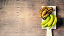 Gelbe und braune Bananen auf einem Brettchen