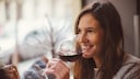Junge Frau nippt an einem Glas mit Rotwein