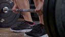 Orientiert am Bizeps-R&uuml;cken-Training von The Rock: Frau beugt sich &uuml;ber Langhantel (Symbolbild)