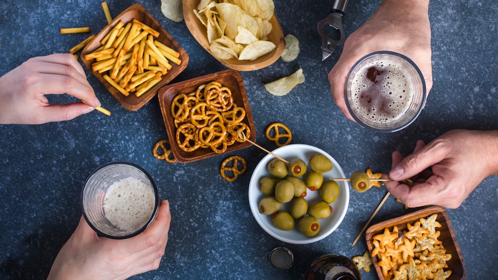 Tisch mit unterschiedlichen Snacks wie Chips, Brezeln und Oliven