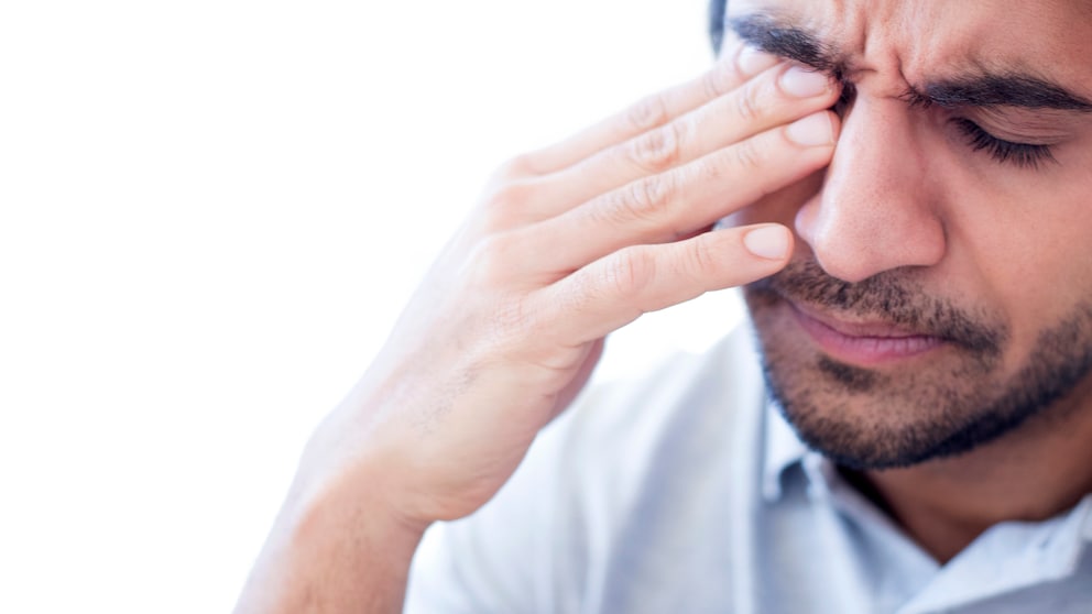 Mann fasst sich unter Schmerzen ans Auge
