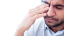 Mann fasst sich unter Schmerzen ans Auge