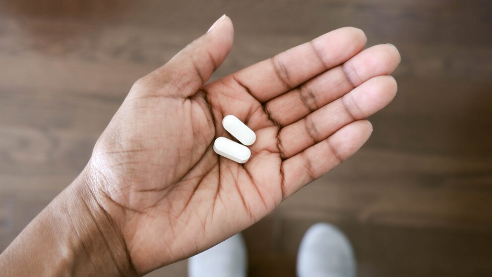 L-Glutamin: Eine Frau hat zwei Pillen in der Hand