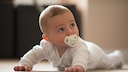 Babys haben Mikroplastik im Körper: Ein Säugling mit Schnuller im Mund liegt auf dem Bauch