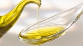 Olivenöl tröpfelt auf einen Löffel