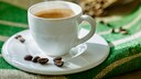 Kaffee entkoffeinieren: Eine weiße Kaffeetasse mit Kaffeebohnen im Hintergrund