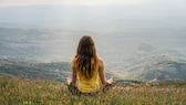 Stresslevel: Rückansicht einer Frau mit langen Haaren meditierend