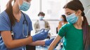 Biontech Jugendliche: Eine junges Mädchen mit Maske bekommt eine Spritze