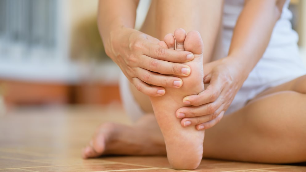 Burning-Feet-Syndrom: Frau reibt sich den Fuß