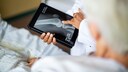 Arzt zeigt älterer Patientin Knochenschwund auf einem Röntgenbild