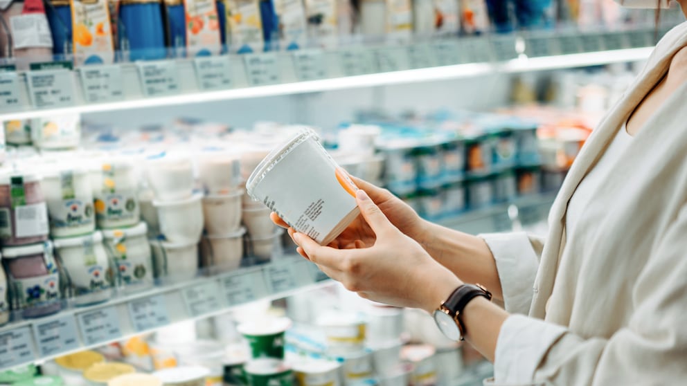Milchprodukte Diabetesrisiko: Frau steht vor einem Supermarktregal und hält einen Joghurt in der Hand