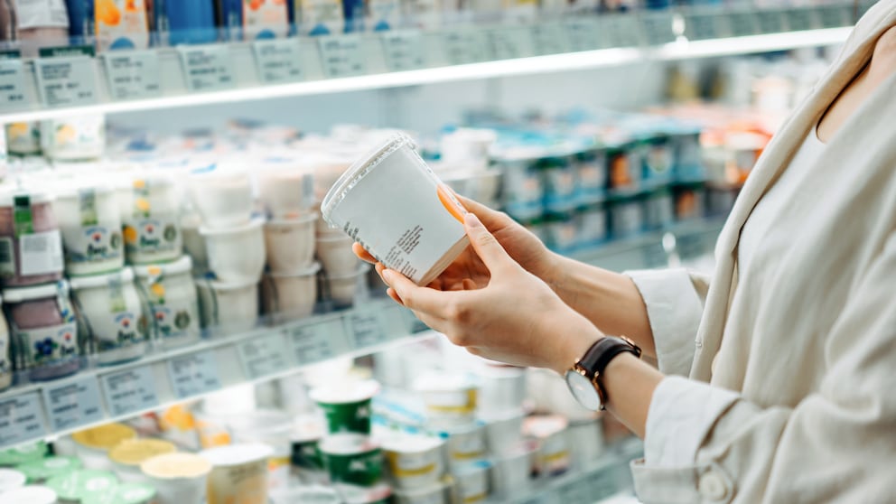 Milchprodukte Diabetesrisiko: Frau steht vor einem Supermarktregal und hält einen Joghurt in der Hand