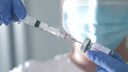 Corona dritte Impfung: Eine Frau zieht eine Spritze mit Corona-Impstoff auf
