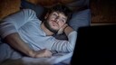 Revenge Bedtime Procrastination: Mann liegt im Bett und nutzt einen Laptop