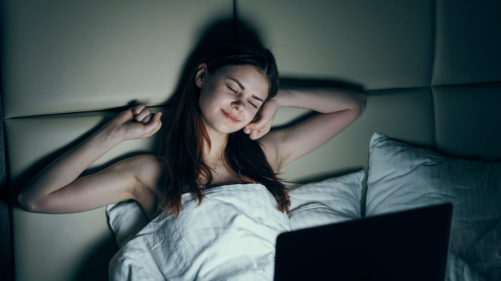 Frau schaut im Bett ein ASMR-Video