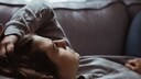 Eine erschöpfte junge Frau liegt auf dem Sofa