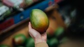 Eine Frau hält eine Mango in der Hand