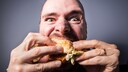 Ein Mann verschlingt einen Burger
