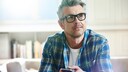 Vitamin B12 Depressionsrisiko: Mann mittleren Alters und mit Brille im Wohnzimmer