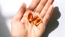 Vitamin D Autoimmunerkrankungen: Eine Hand hält Kapseln mit Fischöl