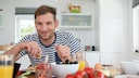 Lebensmittel Männer: ein Mann sitzt an einem gedeckten Frühstückstisch