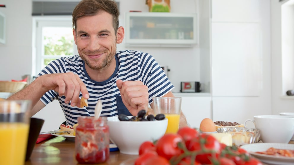 Lebensmittel Männer: ein Mann sitzt an einem gedeckten Frühstückstisch