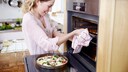 Frau schiebt Pizza in den Ofen