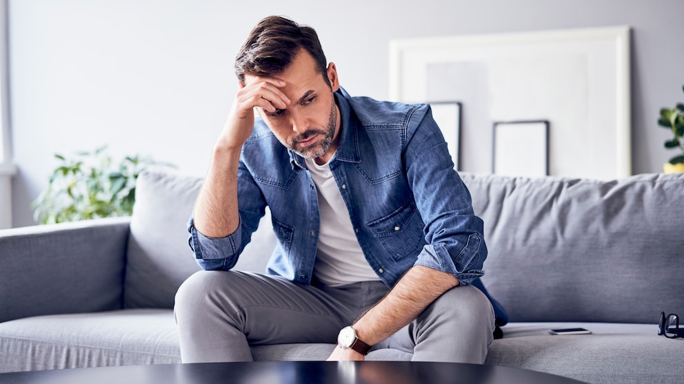 Trennungen Männer: Ein Mann sitzt nachdenklich auf dem Sofa