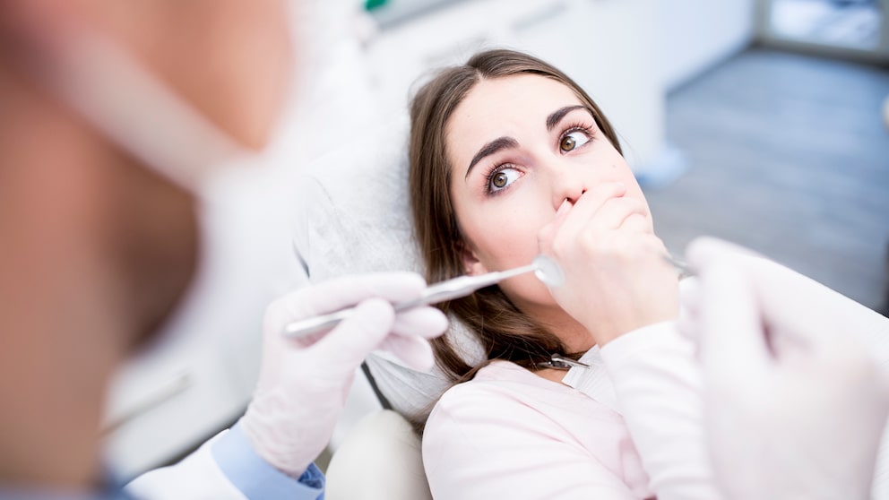 was hilft gegen Mundgeruch: Frau beim Zahnarzt hält sich Mund zu