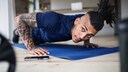 Ein junger Mann macht im Wohnzimmer Liegestütze