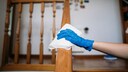 Hand wischt mit Tuch über Treppengeländer aus Holz