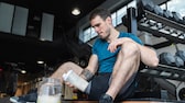 Ein junger Mann mit Protein-Shake im Gym