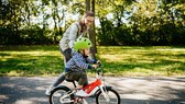 kauf kinderfahrrad: Mutter schiebt ihr Kind auf dem Rad