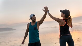 Junges sportliches Paar macht High Five am Strand