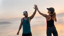 Junges sportliches Paar macht High Five am Strand