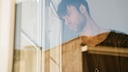 Lockdowns psychische Erkrankungen: Mann schaut traurig aus dem Fenster