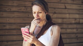 Impfzertifikat verlängern: Frau schaut auf ihr Handy