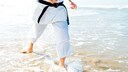 Mann im Karate-Gi läuft durch Meeresbrandung