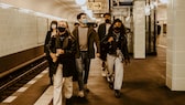 warum nicht mit corona infiziert: Gruppe junger Menschen mit Masken in einer U-Bahn-Station